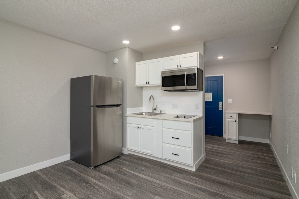 a kitchen with white cabinets and a stainless steel refrigerator