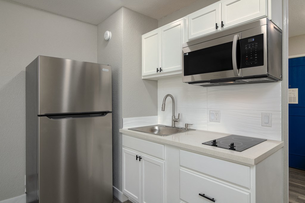 a kitchen with white cabinets and a stainless steel refrigerator
