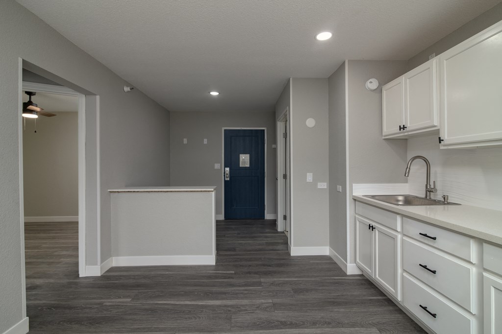a renovated kitchen with white cabinets and a blue door