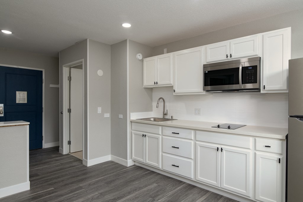 a kitchen with white cabinets and a sink and a microwave
