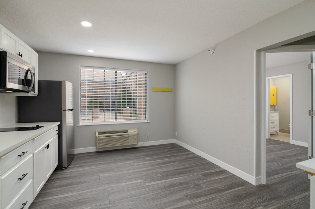 an empty kitchen and living room with a window and white cabinets