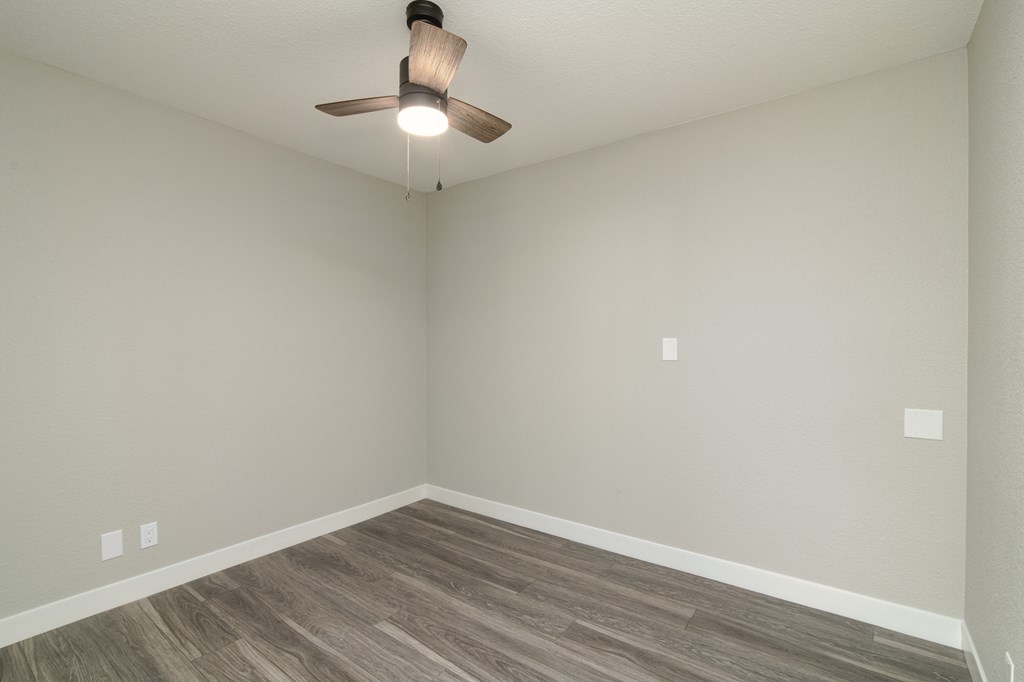an empty room with wood flooring and a ceiling fan