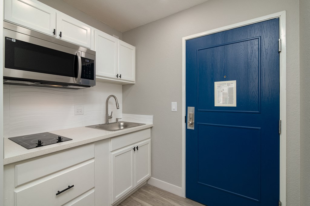 a kitchen with a blue door and a sink and a microwave