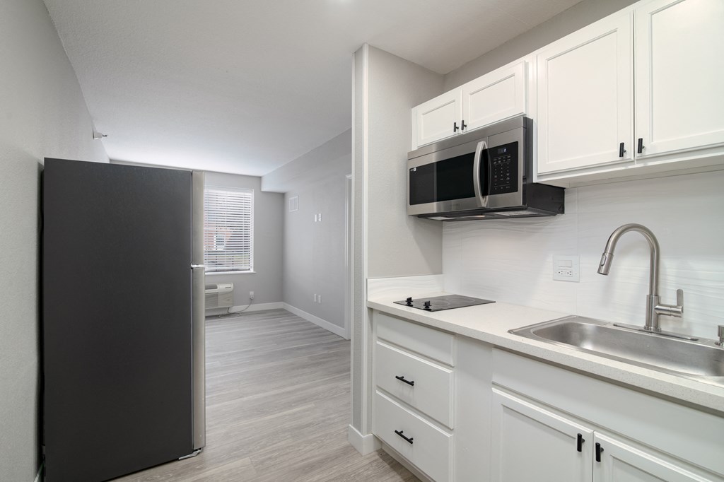 a kitchen with white cabinets and a sink and a refrigerator