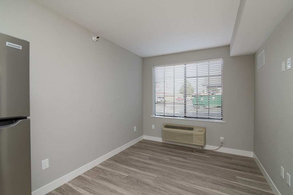 the living room of an apartment with a window and wood flooring