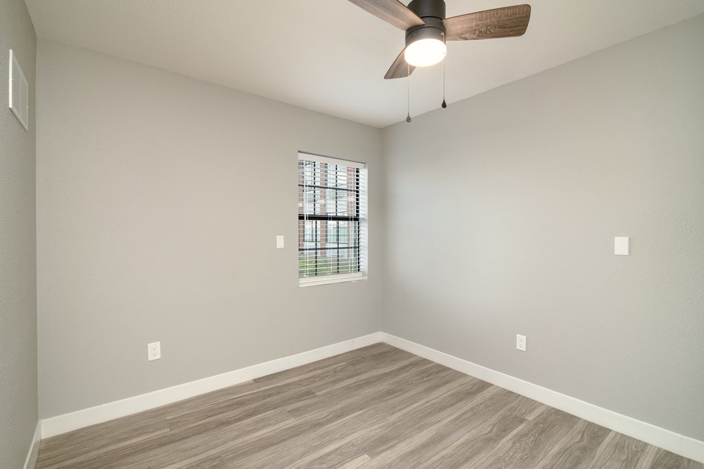 an empty living room with wood floors and a ceiling fan