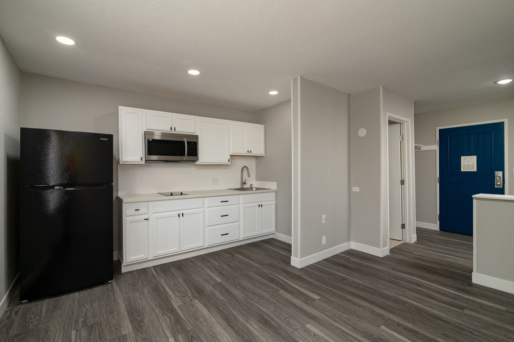 a kitchen with white cabinets and a black refrigerator