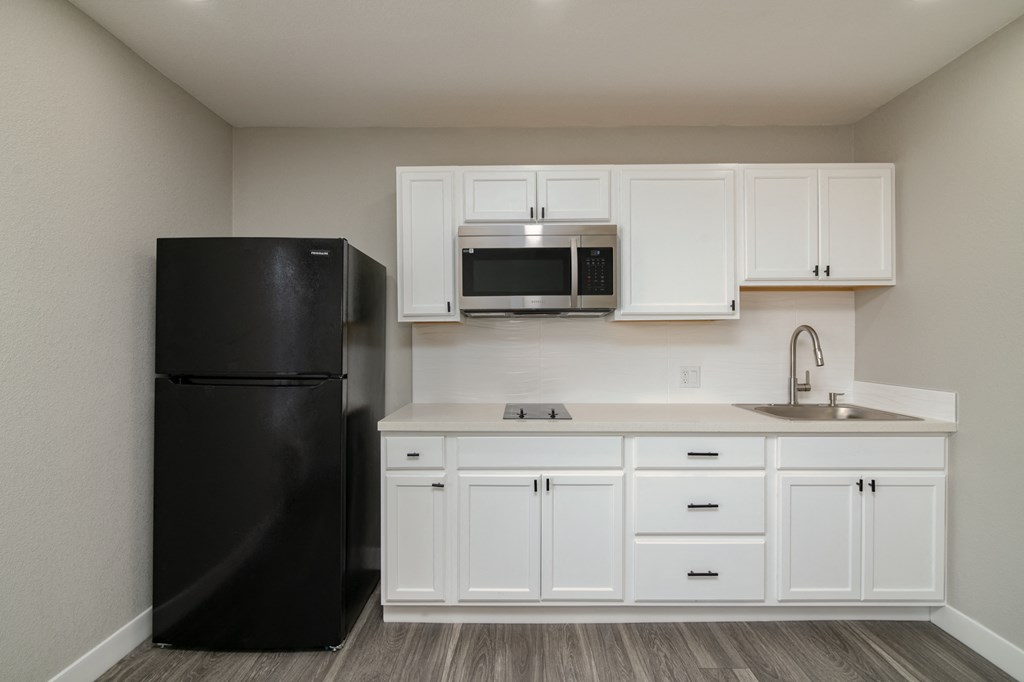 a kitchen with white cabinets and a black refrigerator