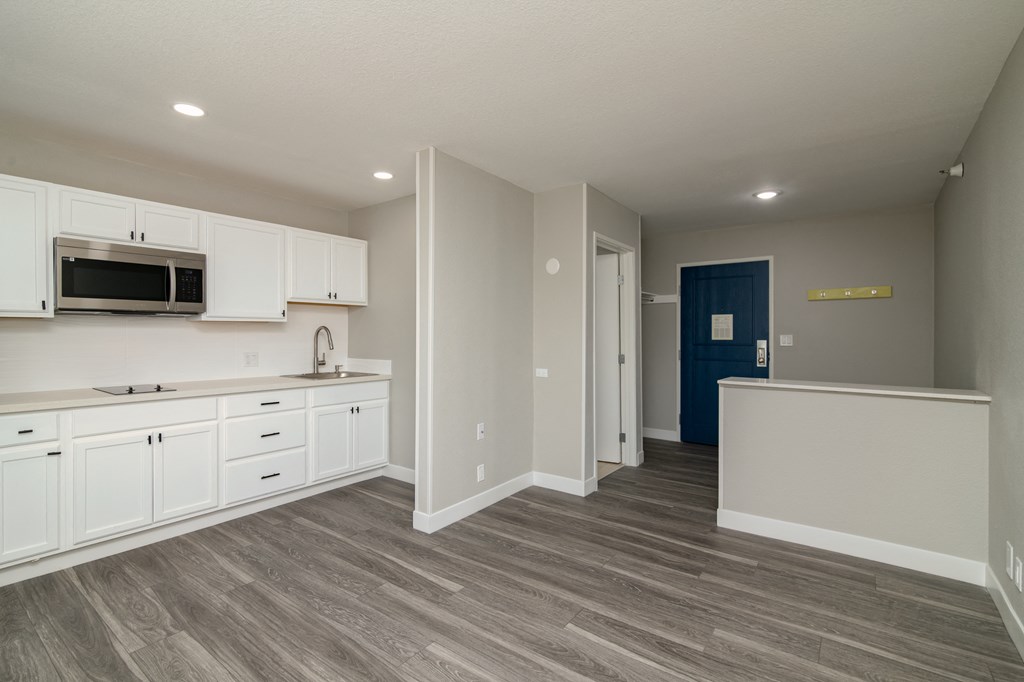 an empty kitchen with white cabinets and a blue door
