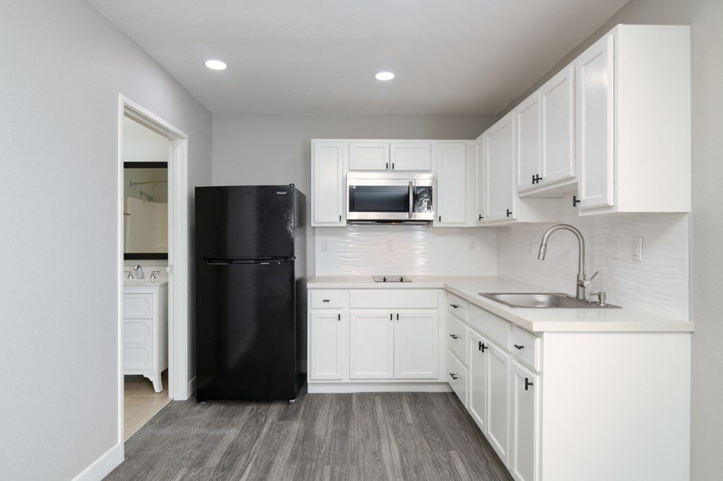 a kitchen with white cabinets and a black refrigerator