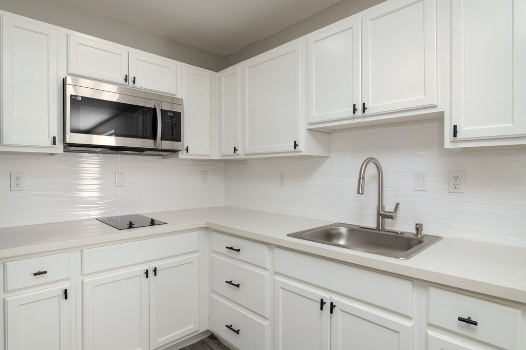 a kitchen with white cabinets and a sink and a microwave