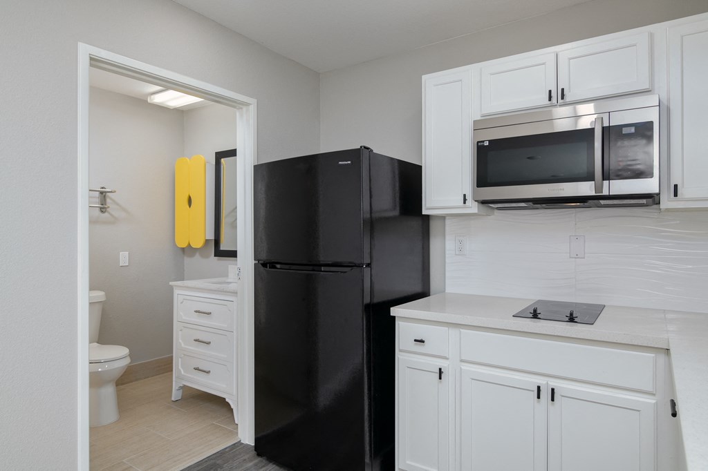a kitchen with white cabinets and a black refrigerator