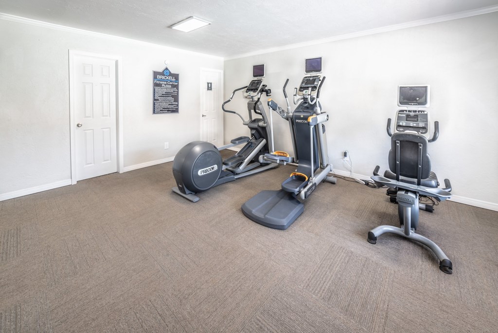 A room with a treadmill, elliptical trainer and a stationary bike.