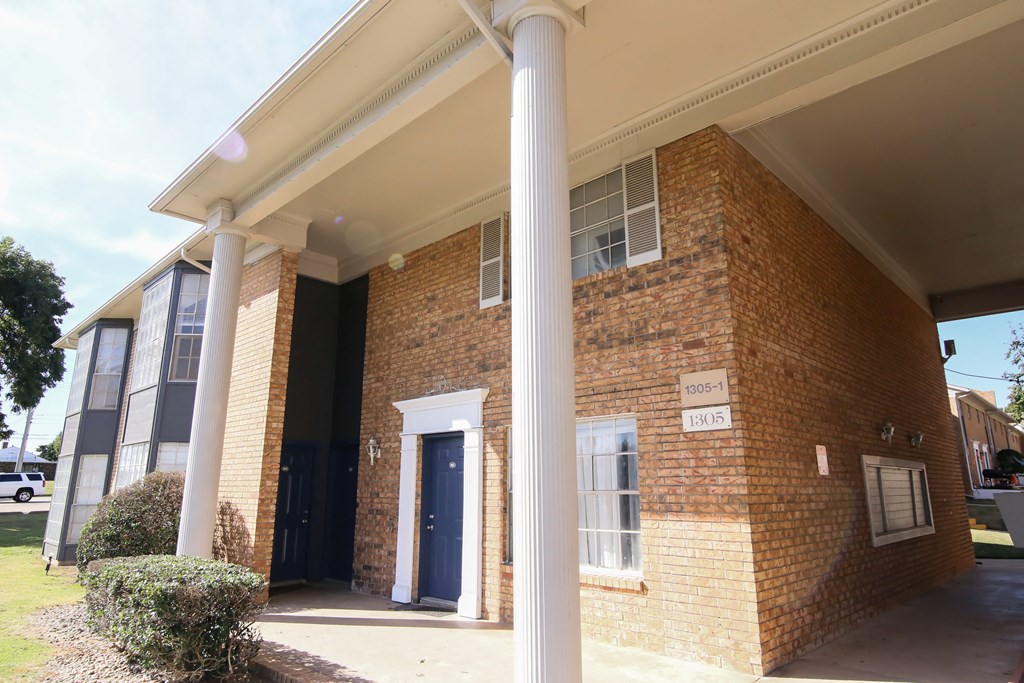 a brick building with two pillars and a blue door