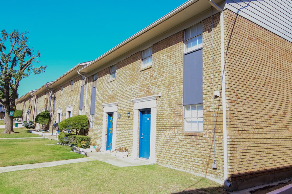 a brick building with a blue door and a lawn