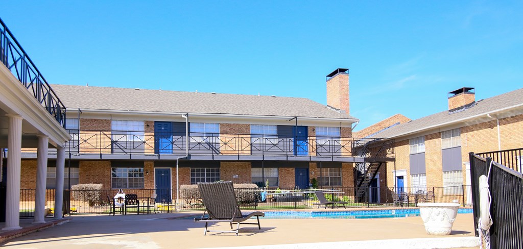 a building with a pool and chairs in front of it