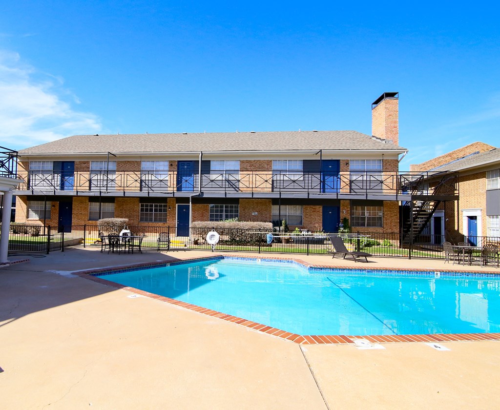 a swimming pool in front of a building with a resort style pool