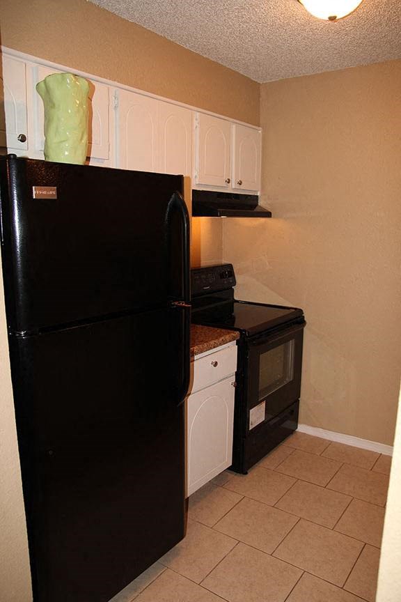 a kitchen with a black refrigerator and a stove