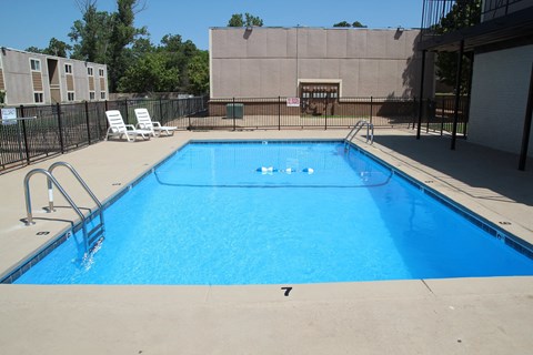 the pool at our apartments has a large blue pool and chairs
