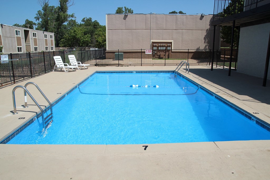 the pool at our apartments has a large blue pool and chairs