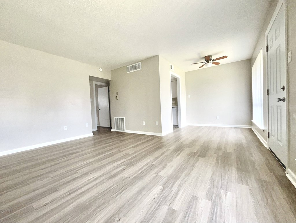 an empty living room with wood floors and a ceiling fan
