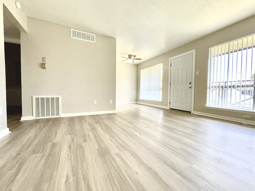 an empty living room with hardwood flooring and a window