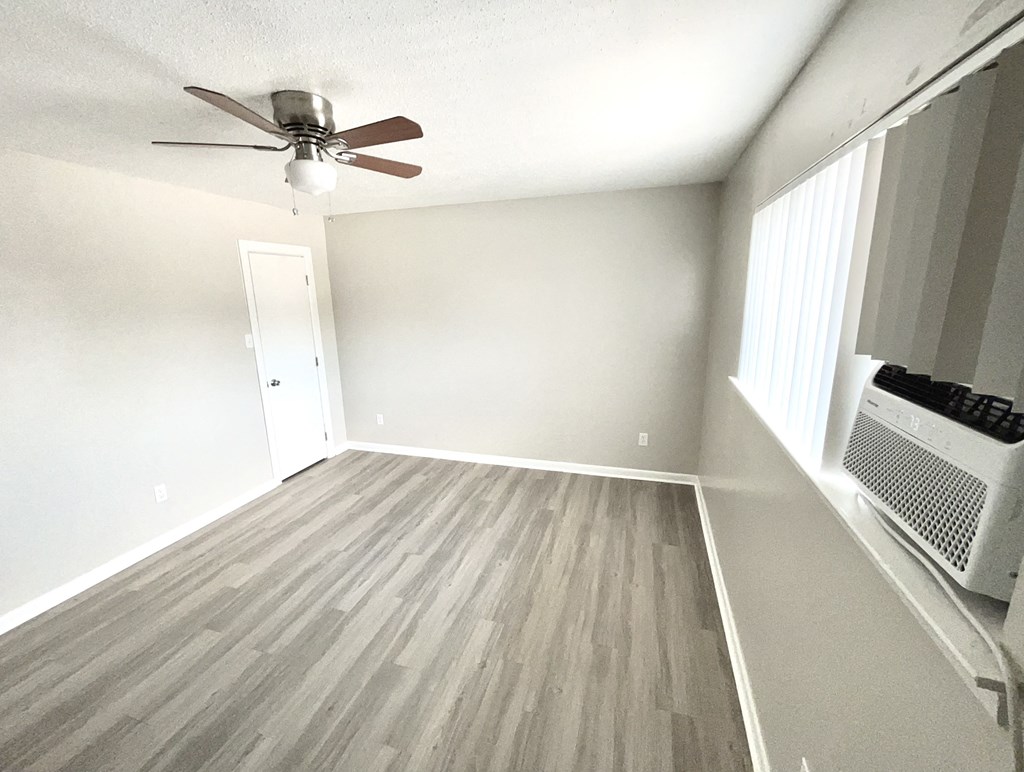 an empty living room with wood floors and a ceiling fan