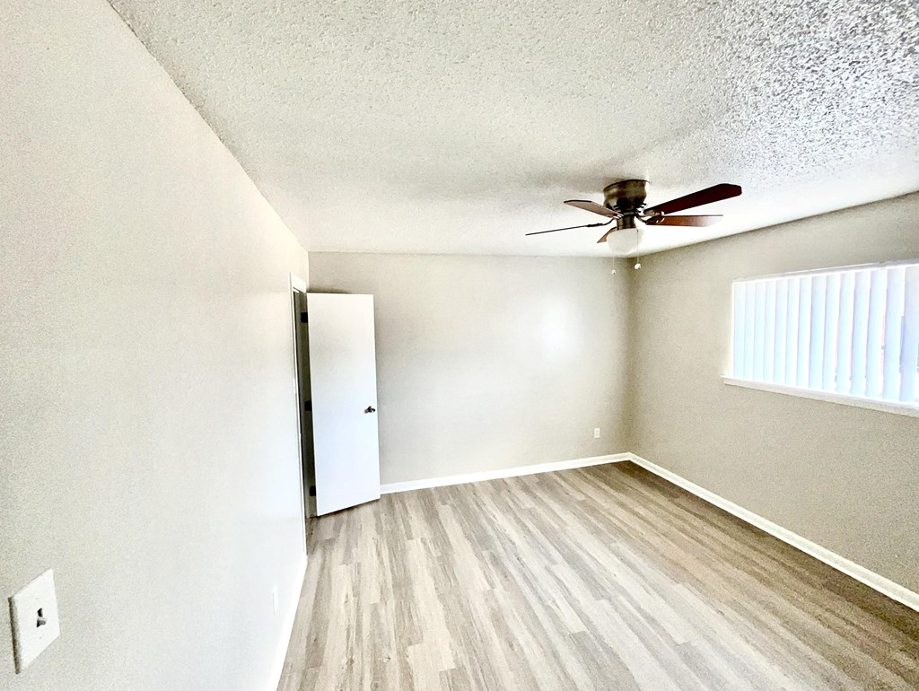 an empty living room with a ceiling fan and a door to a closet