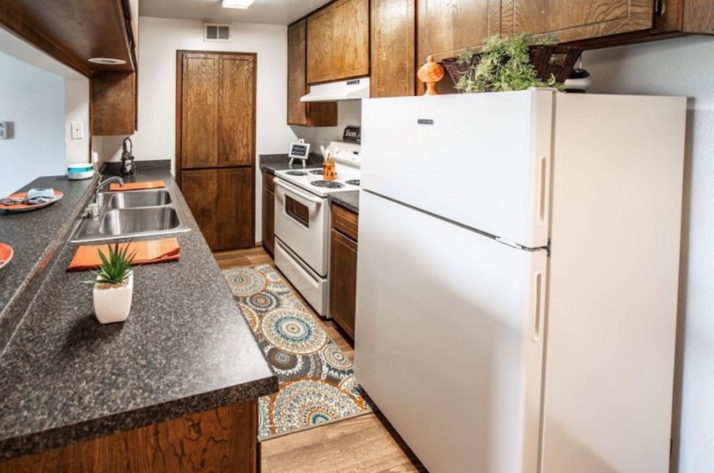 A kitchen with a white fridge and wooden cabinets.