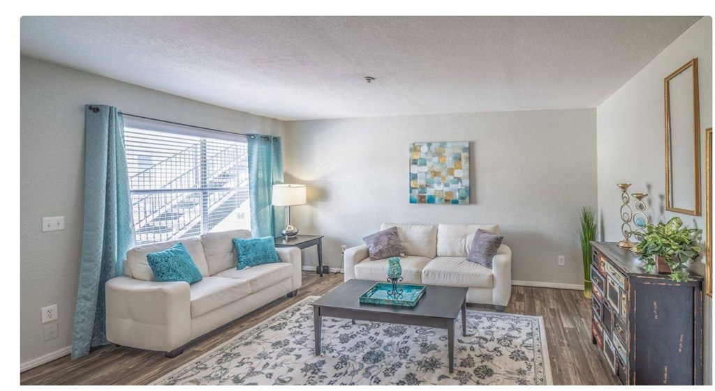 A living room with a white couch, a coffee table, and a painting on the wall.
