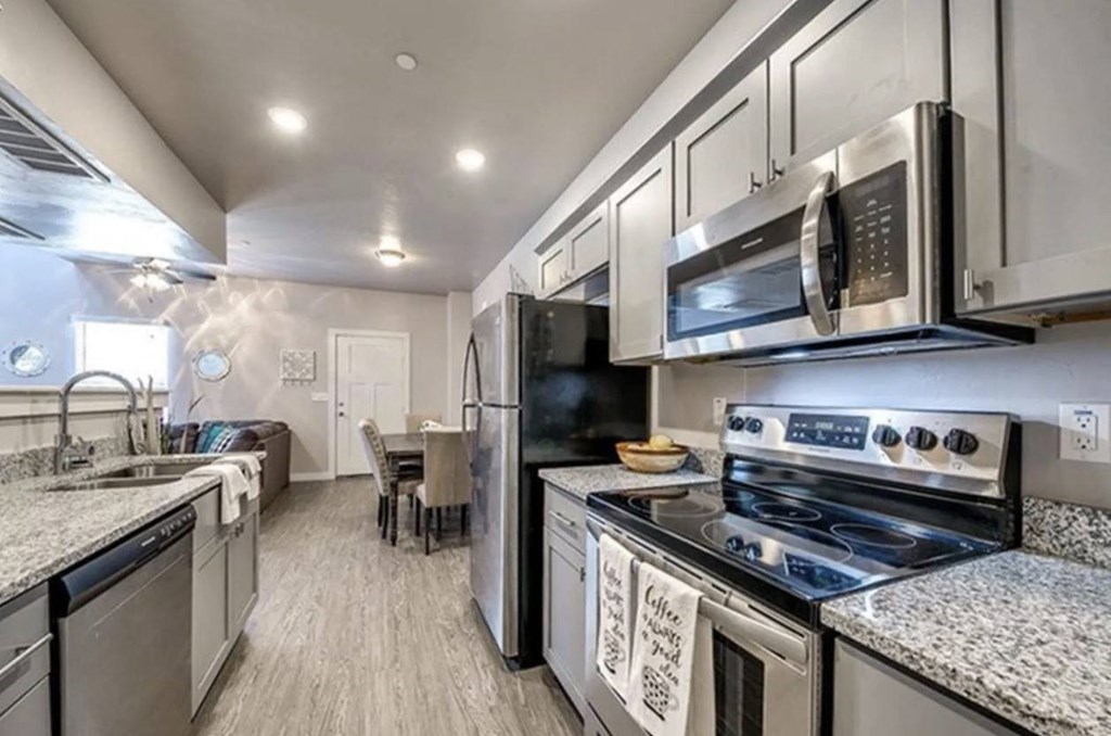 A modern kitchen with stainless steel appliances and a dining area.