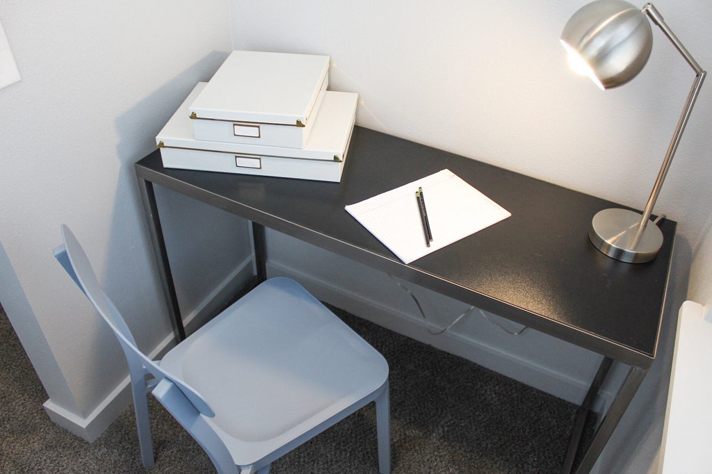 a desk with two boxes and a notebook and a chair in a room