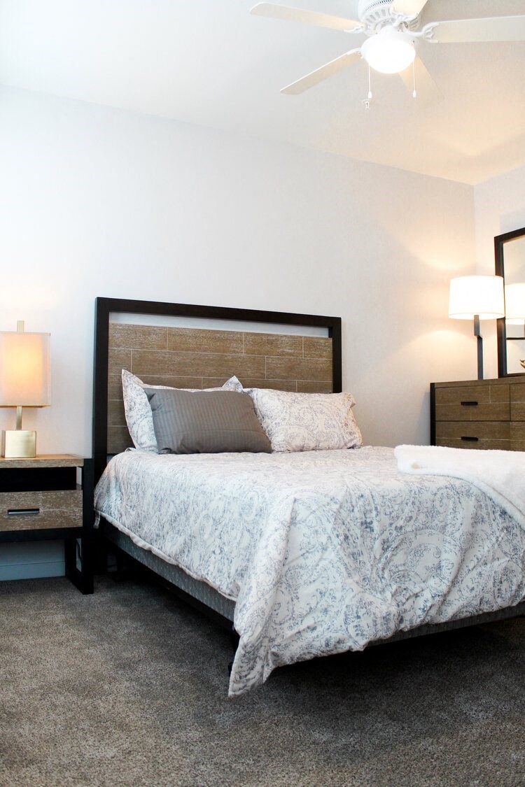 a bedroom with a bed and two night stands and a ceiling fan