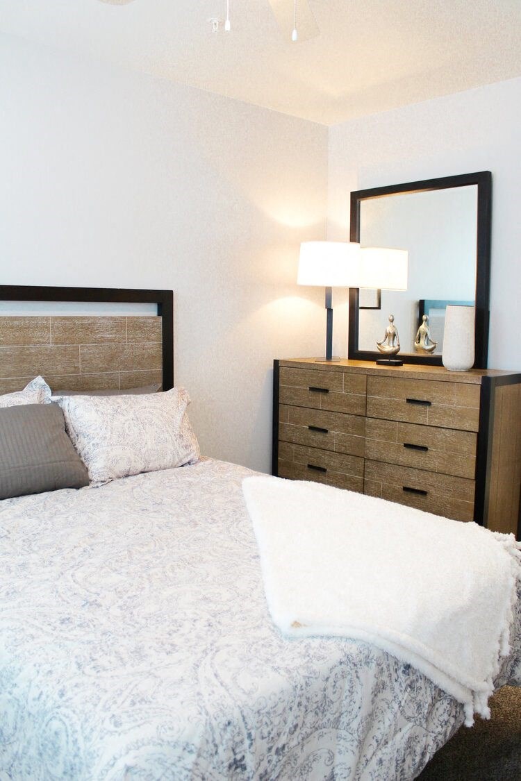 a bedroom with a bed and dresser with a mirror