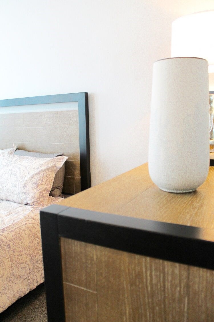 a white lamp sitting on a table next to a bed