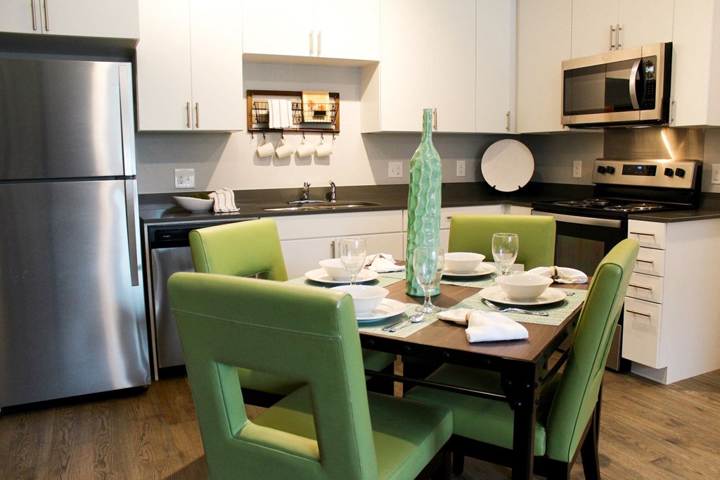a kitchen with stainless steel appliances and a table with green chairs
