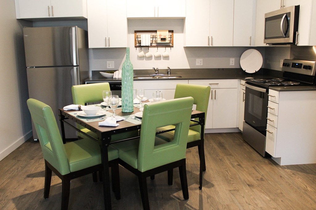 an open kitchen and dining area with a table and chairs and a counter top microwave