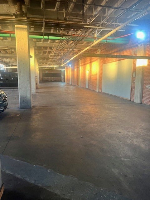 A long, empty parking garage with concrete floors and brick walls.