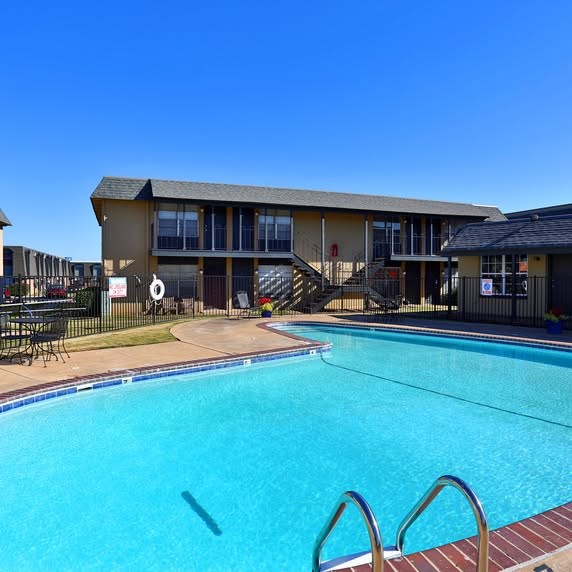 A swimming pool in front of a building with a black fence around it.