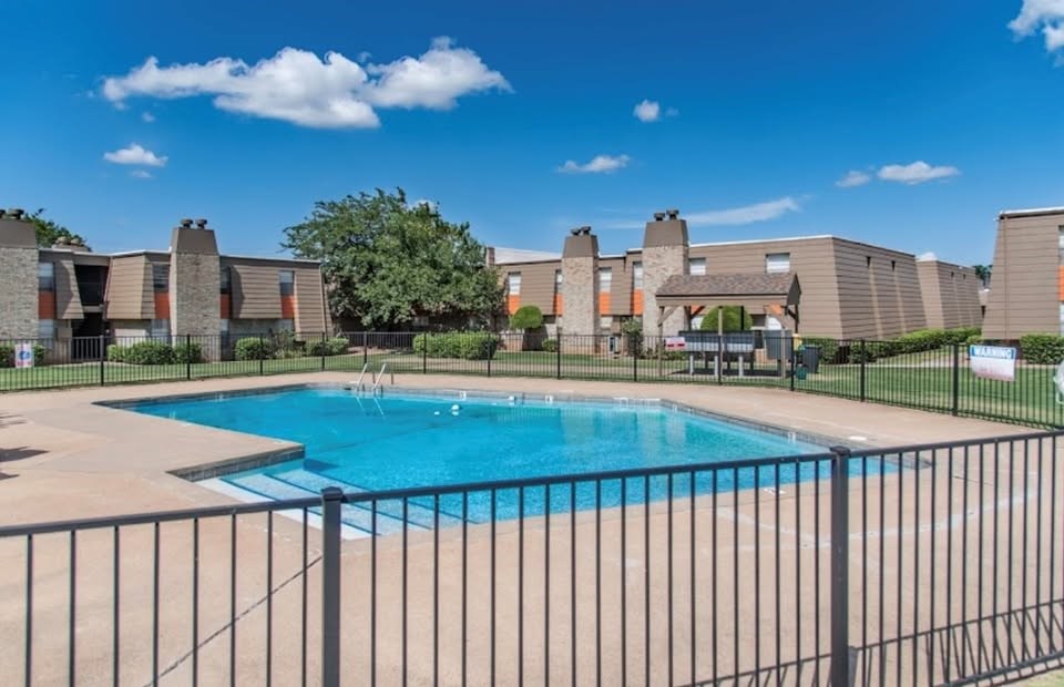 A swimming pool surrounded by a fence and apartment buildings.