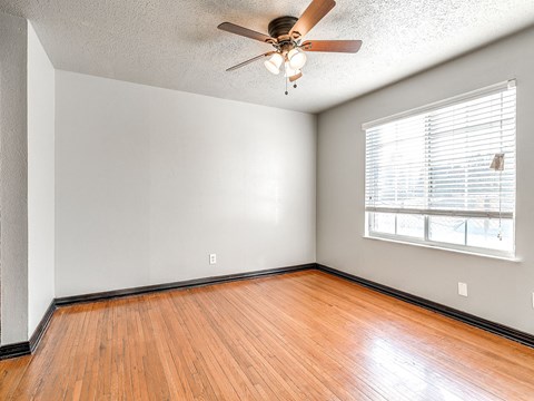 the living room of an empty home with wood floors and a ceiling fan