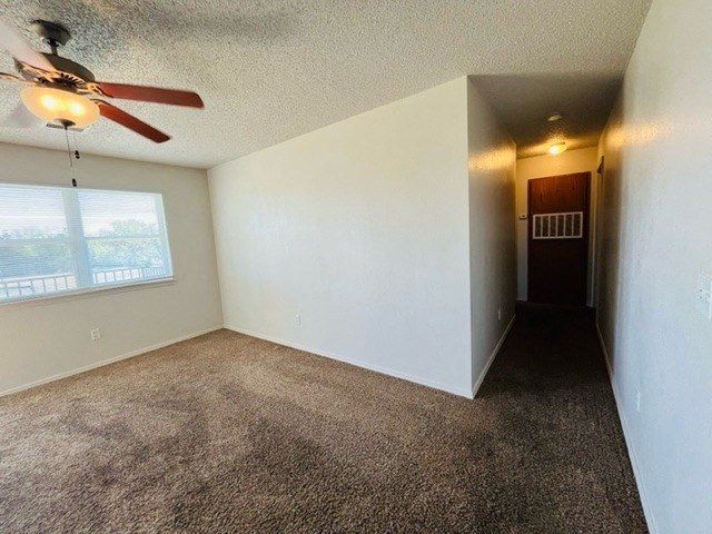 an empty living room with a ceiling fan and a window
