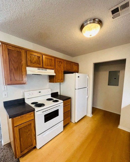 a kitchen with white appliances and wooden cabinets and a refrigerator