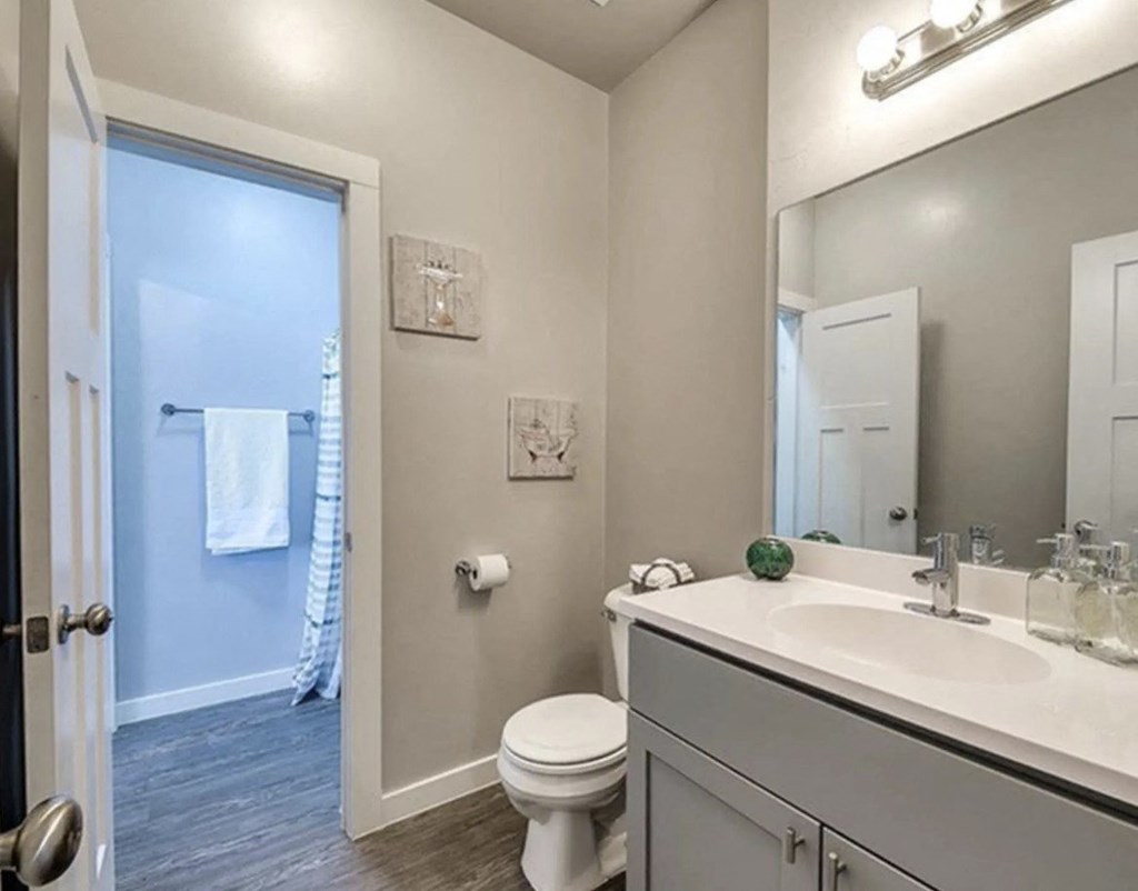 A bathroom with a toilet, sink, and mirror.
