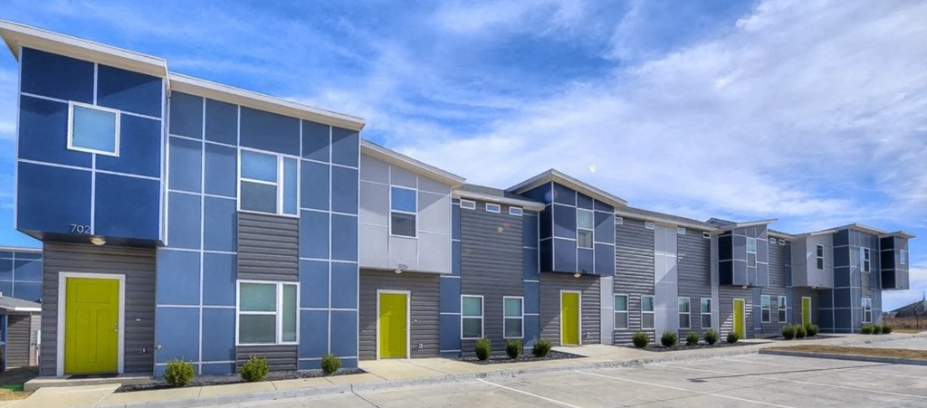 A row of modern townhouses with blue and grey exteriors and yellow doors.