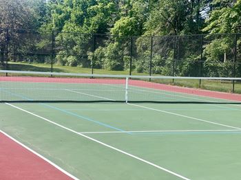 A tennis court with a net and green and red surface.