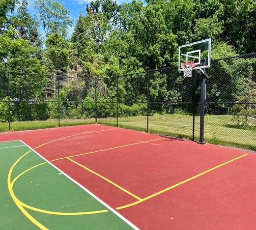 A basketball court with a red surface and yellow lines.