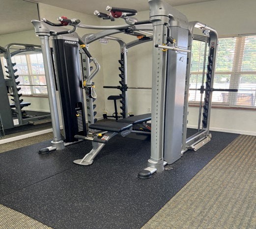 A gym with a black and grey floor and a large mirror on the wall.