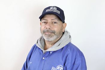 A man wearing a blue shirt and a cap with the word "PROPOSAL" written on it.