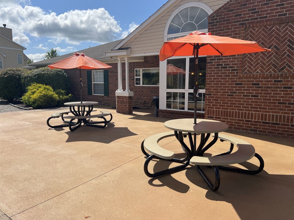 two tables with umbrellas outside of a brick building